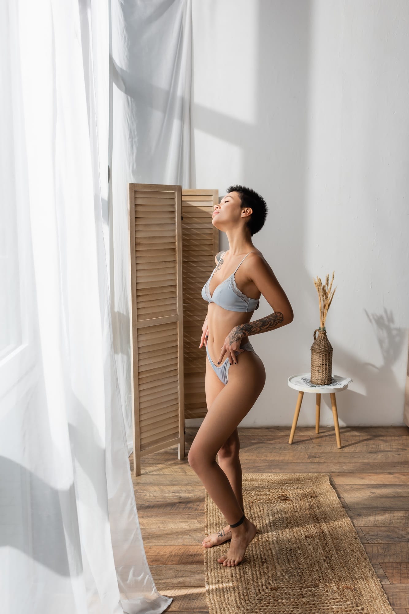 full length of stunning woman with sexy tattooed body enjoying natural light