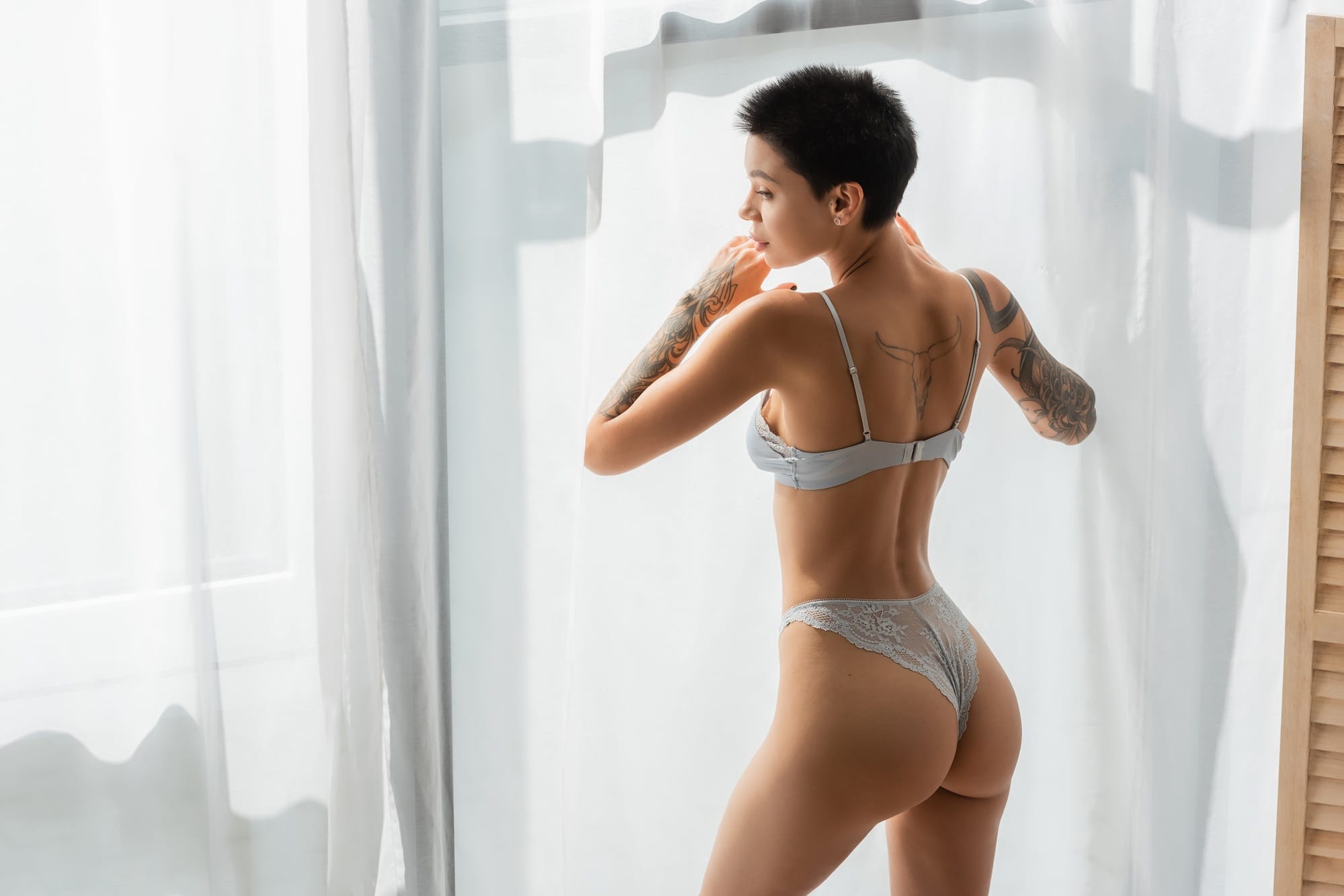 young and stunning woman with sexy tattooed body and short brunette hair wearing lace panties